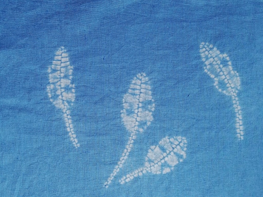 From Nature to Fabric: Creating Captivating Shibori Leaf Motifs 10 4 white shibori leaf motifs on a blue fabric background