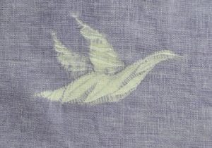 Flying shibori goose pattern against a dyed mauve fabric