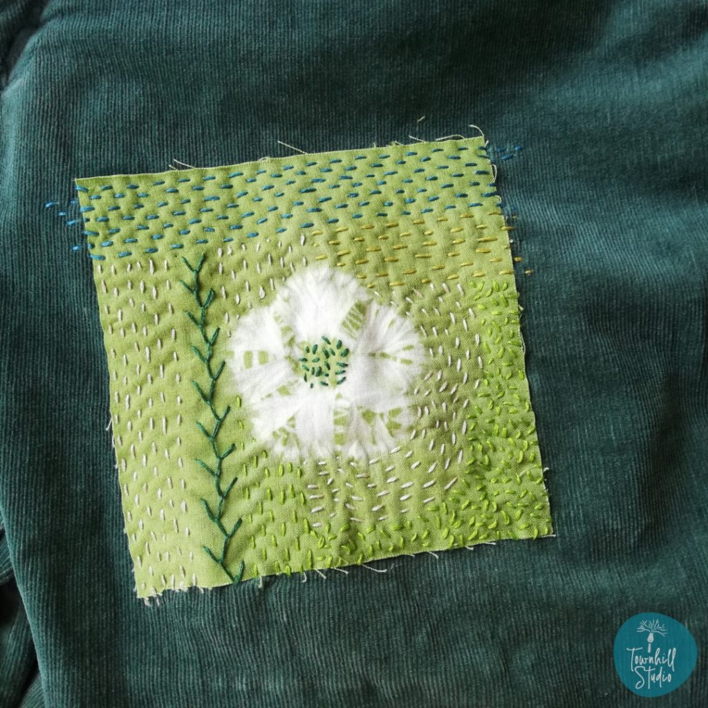 Discover Inspiring Ideas for Mending with Shibori Patterns 5 shows hand embroidered shibori flower patch on green jeans