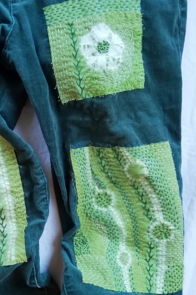 Discover Inspiring Ideas for Mending with Shibori Patterns 9 shows dark green jeans with two shibori embroidered patches