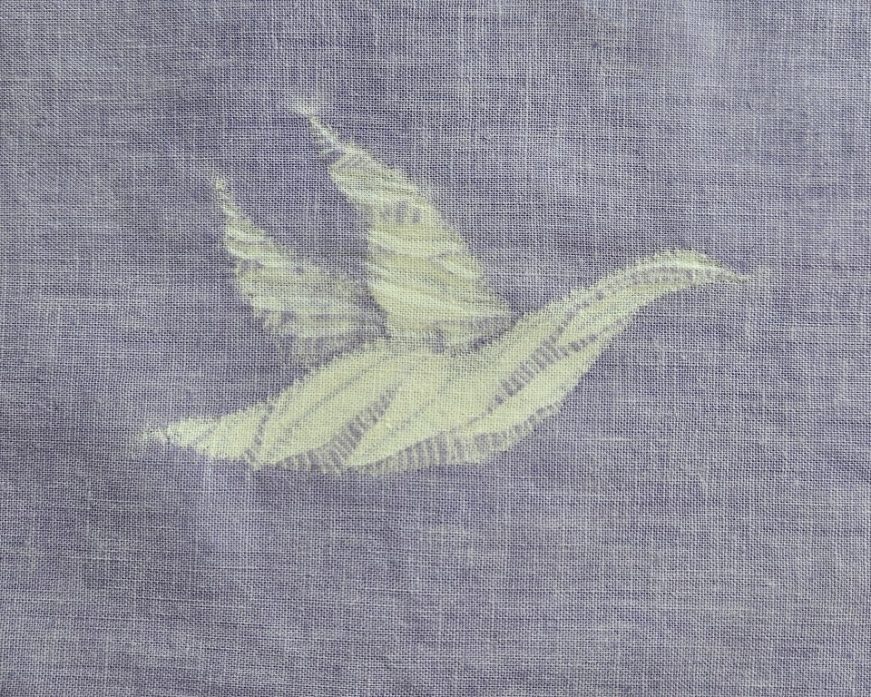 Flying shibori goose pattern against a dyed mauve fabric