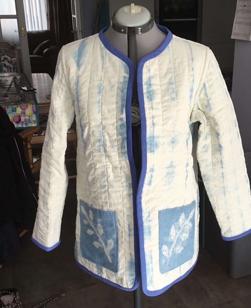 Cream and pale blue quilted jacket with blue leaf sprigs on the pockets.