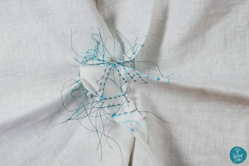 Winter Magic: Crafting Your Own Sparkling Shibori Snowflake 3 White fabric showing individual lines of stitching to create feather effect of snowflake spines.